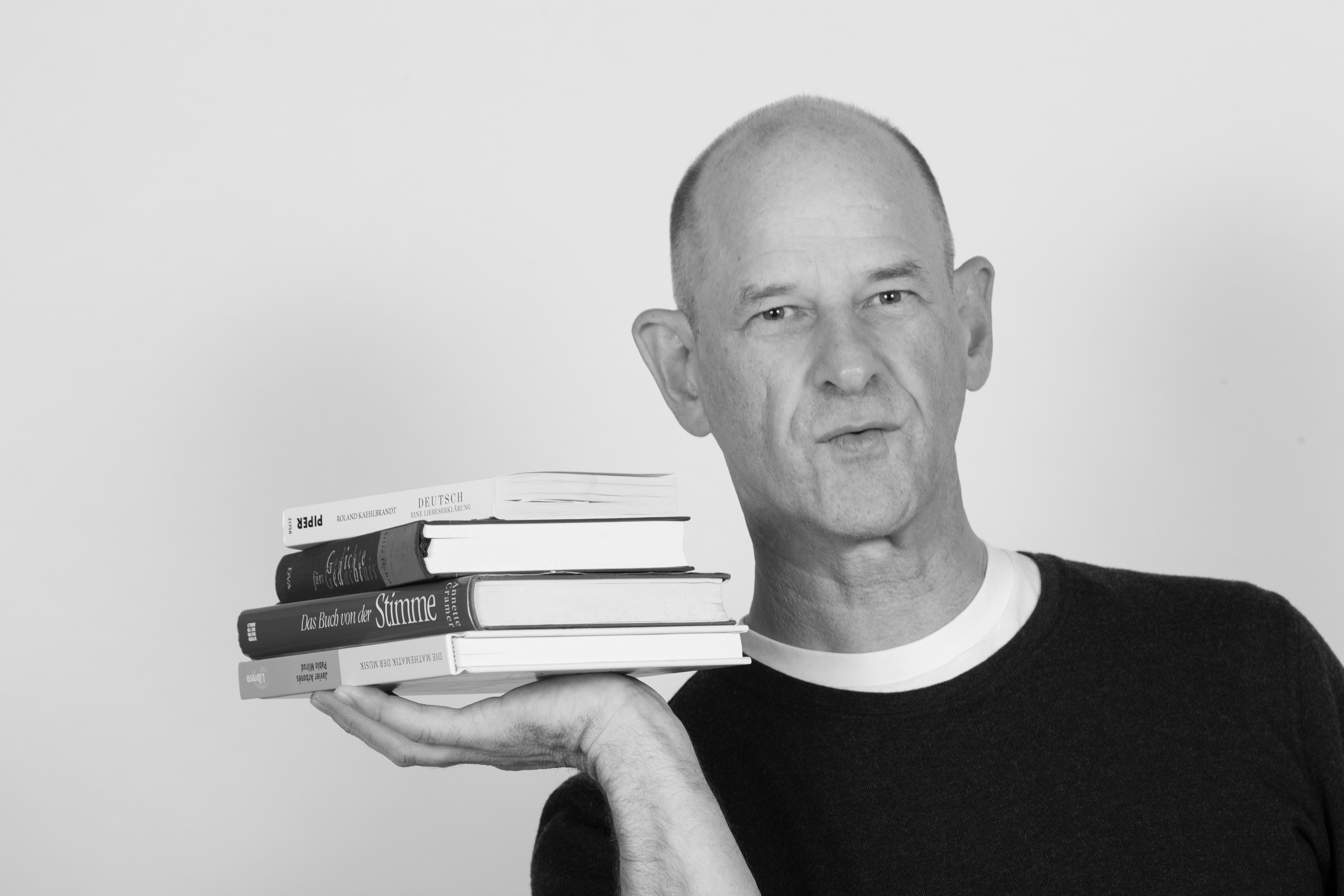 Sven Hemprich mit einem Stapel Bücher über Stimme und Sprache in der Hand